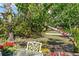 Outdoor patio area with a table and chair shaded by a tree with flowering vines at 6796 Gasparilla Pines Blvd # 45, Englewood, FL 34224