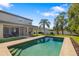 A backyard pool with a covered patio and seating is surrounded by lush landscaping at 6807 46Th E Ter, Bradenton, FL 34203