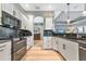 Beautiful kitchen with white cabinetry, modern appliances, granite countertops, and wood flooring, with an open concept design at 779 Fordingbridge Way, Osprey, FL 34229