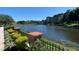 Scenic view of a pond surrounded by lush greenery, brick pillars, and a wrought iron fence at 779 Fordingbridge Way, Osprey, FL 34229