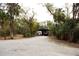 Wide driveway leading to a covered parking area with a large truck, amidst a serene, wooded landscape at 8570 Tropicaire Blvd, North Port, FL 34291