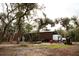 Exterior view of the property with mature tree coverage showing covered parking area, truck, and construction equipment at 8570 Tropicaire Blvd, North Port, FL 34291