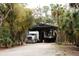 Exterior of property featuring large truck under covered parking, surrounded by mature trees and lush landscaping at 8570 Tropicaire Blvd, North Port, FL 34291