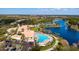 Aerial view of community clubhouse, pool, parking and tennis near a lake at 8849 Etera Dr, Sarasota, FL 34238