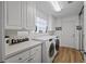 Clean laundry room with lots of cabinets, laundry sink, and light hardwood flooring at 8849 Etera Dr, Sarasota, FL 34238