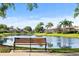 Scenic view of a peaceful pond with a bench, palm trees, and waterfront homes in the background at 8849 Etera Dr, Sarasota, FL 34238