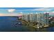 Beautiful aerial view of white condo buildings with docks, palm trees and a pool, against a blue water backdrop at 888 Blvd Of The Arts # 1608, Sarasota, FL 34236