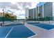 Multiple tennis courts with a tall building and green fence in the background at 888 Blvd Of The Arts # 1608, Sarasota, FL 34236