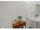 Small bathroom with pedestal sink, wooden accent table, and large mirror at 8995 Milestone Dr, Sarasota, FL 34238