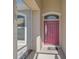 Covered entryway featuring a vibrant red front door with sidelight and transom window, with neutral stucco and white trim at 10726 Old Grove Cir, Bradenton, FL 34212