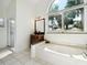 Bright bathroom featuring a large soaking tub under an arched window at 1358 Berkshire Ct, Venice, FL 34292