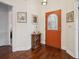Inviting foyer with decorative table, art, and a vibrant orange door with glass insert at 1358 Berkshire Ct, Venice, FL 34292