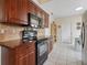 Galley-style kitchen with wood cabinetry, tile backsplash, and black appliances at 1358 Berkshire Ct, Venice, FL 34292