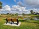 Scenic view of a tranquil pond with a bench, lush greenery, and surrounding residential community at 1358 Berkshire Ct, Venice, FL 34292
