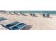 Relaxing beach view with rows of lounge chairs and striped umbrellas at 225 Sands Point Rd # 6204, Longboat Key, FL 34228