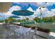 Outdoor patio seating under umbrellas overlooking impeccably maintained tennis courts and lush green landscaping at 225 Sands Point Rd # 6204, Longboat Key, FL 34228