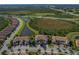 Community aerial view with pristine lake views, lush landscaping, and tile roofed townhome exteriors at 23189 Banbury Way # 203, Venice, FL 34293
