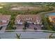 Aerial view of townhomes featuring tile roofs, brick driveways, and lush landscaping near a tranquil lake at 23189 Banbury Way # 203, Venice, FL 34293