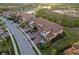 Aerial view of townhomes featuring tile roofs, brick driveways, and lush landscaping near a tranquil lake at 23189 Banbury Way # 203, Venice, FL 34293