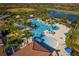 Aerial view of community pool with ample seating, umbrellas, and a beautiful lake in the background at 23189 Banbury Way # 203, Venice, FL 34293