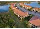 Aerial view of townhomes featuring tile roofs, screened lanais, and lush landscaping in a waterside community at 23189 Banbury Way # 203, Venice, FL 34293