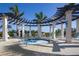 A luxurious hot tub is surrounded by a pergola, lounge chairs, and lush landscaping for ultimate relaxation at 23189 Banbury Way # 203, Venice, FL 34293