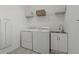Practical laundry room equipped with white washer, dryer, utility sink and overhead storage at 23189 Banbury Way # 203, Venice, FL 34293