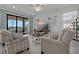 Comfortable living room featuring neutral tones, a large television, and access to a private balcony at 23189 Banbury Way # 203, Venice, FL 34293