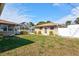 Backyard featuring green grass, lush trees and a white privacy fence at 2347 Sunnyside Pl, Sarasota, FL 34239