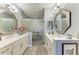Bathroom featuring double sinks with quartz countertops, a glass enclosed shower, and decorative mirrors at 2622 Light Sky Ln, Bradenton, FL 34211