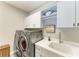 Well-lit laundry room featuring modern washer and dryer, sink, and storage cabinets at 2622 Light Sky Ln, Bradenton, FL 34211