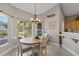 A dining area features natural lighting, a modern chandelier, and a view of the home's landscaped property at 27350 San Carlos Dr, Punta Gorda, FL 33983
