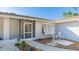 Close-up of the home's entry with a screen door, shuttered window, and a small seating area at 2760 Siesta Dr, Venice, FL 34293