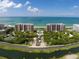 Aerial view of beachfront condos, showcasing community pool, tennis courts, and lush landscaping at 435 L Ambiance Dr # L807, Longboat Key, FL 34228