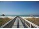 Picturesque beach access with a wooden walkway leading to the ocean with tiki umbrellas on both sides at 435 L Ambiance Dr # L807, Longboat Key, FL 34228