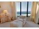 Bedroom area showcasing tranquil ocean views, cozy armchair, ottoman, and traditional wooden dresser at 435 L Ambiance Dr # L807, Longboat Key, FL 34228