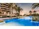 Enjoy the pool surrounded by lush landscaping with palm trees and a sunset in the background at 435 L Ambiance Dr # L807, Longboat Key, FL 34228