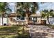 Charming bungalow with a brick driveway, a cozy deck, and lush tropical landscaping at 445 88Th N Ave, St Petersburg, FL 33702