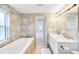 Bright bathroom with double sinks, bathtub and natural stone tile at 5107 Saint Albans Ave, Sarasota, FL 34242
