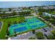 Aerial view of well-maintained tennis courts surrounded by lush landscaping and a clear ocean view in the background at 5282 Beach Se Dr # D, St Petersburg, FL 33705