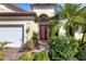 Close up of a home's entryway, highlighting a decorative front door, exterior lighting, and lush surrounding plants at 8079 36Th Street E Cir, Sarasota, FL 34243