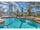 Sparkling pool with waterfall feature, set within a screened enclosure and lush landscaping at 907 Garland Ave, Nokomis, FL 34275