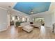 Open floor plan showing the kitchen, dining area, and living room with a blue tray ceiling and wood-look tile flooring at 12514 Goldenrod Ave, Bradenton, FL 34212