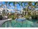 Stunning pool area enclosed with glass walls, tropical plants, arches, and comfortable outdoor seating at 13315 Palmers Creek Ter, Lakewood Ranch, FL 34202