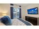 Comfortable bedroom with a mounted TV, dark dresser, blue accents, and shuttered window at 14510 Leopard Creek Pl, Lakewood Ranch, FL 34202