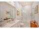 Bright bathroom with a glass enclosed shower-over-tub, a white vanity with double sinks, and framed artwork at 15115 Montello Way, Lakewood Ranch, FL 34211