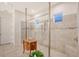 Modern bathroom featuring a glass enclosed shower with light beige tiling and decorative accent tiles, and a marble topped wood cabinet at 15115 Montello Way, Lakewood Ranch, FL 34211