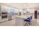 Modern kitchen featuring white cabinets, stainless steel appliances, tile backsplash, and a large island with seating at 15115 Montello Way, Lakewood Ranch, FL 34211