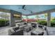 Relaxing outdoor lounge with comfortable seating, fireplace, TV and views of tropical landscaping and sunny blue skies at 15115 Montello Way, Lakewood Ranch, FL 34211