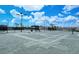 Outdoor tennis court with a gray surface, surrounded by netting, and equipped with lighting for evening play at 15115 Montello Way, Lakewood Ranch, FL 34211